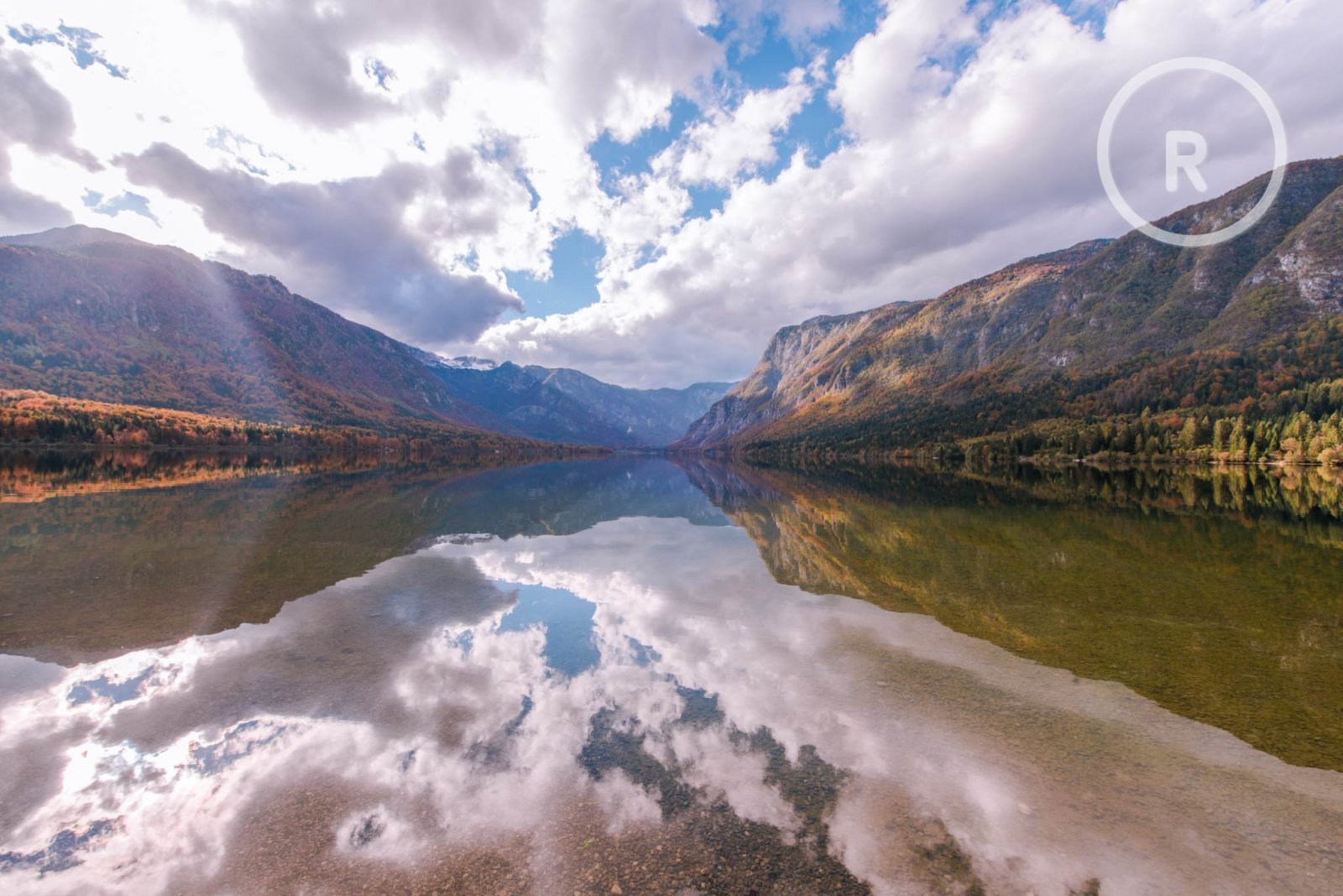 Before: A circular logo with the letter R in the upper right of a lake and mountain landscape